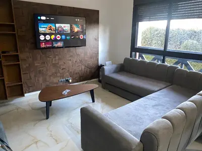 a living room with a couch and a tv at Cosy appartement avec piscine in Marrakech