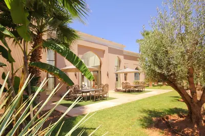 a building with tables and chairs in a yard at Palais Les Orchidées - Villa de Luxe à 15 minutes du Centre in Marrakech