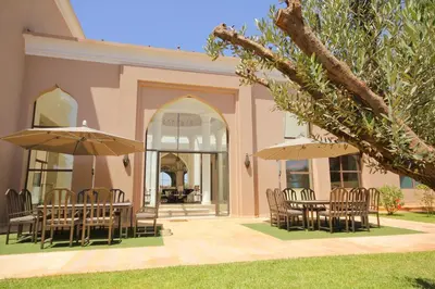 a patio with tables and chairs and umbrellas at Palais Les Orchidées - Villa de Luxe à 15 minutes du Centre in Marrakech