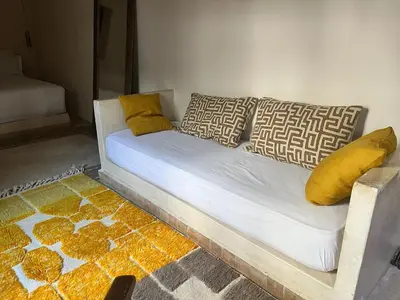 a white couch with yellow pillows and a rug at Riad des Sources in Marrakech