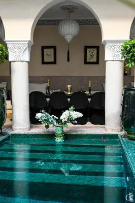 a pool in the middle of a room with chairs at Riad des Sources in Marrakech