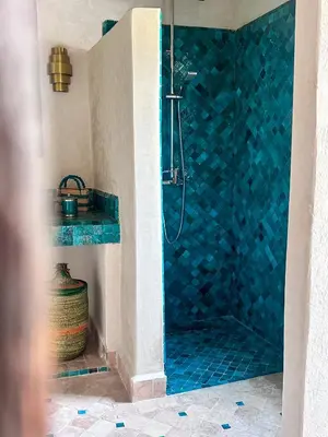 a bathroom with a shower with a blue tiled wall at Riad des Sources in Marrakech