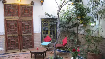 a patio with two chairs and a table and a door at Riad Maizie in Marrakech