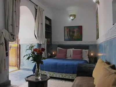 a bedroom with a bed and a vase of flowers on a table at Riad Maizie in Marrakech