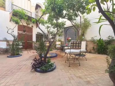 a patio with a table and chairs and trees at Riad Maizie in Marrakech
