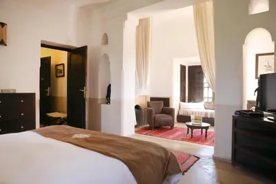 a bedroom with a bed and a chair and a television at Villa Le Perroquet Bleu in Marrakech