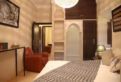 a bedroom with a bed and a couch and a chair at Villa Le Perroquet Bleu in Marrakech