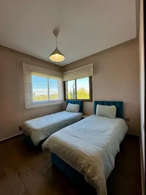 two beds in a room with two windows at Exceptional Golf View Apartment, Prestigia in Marrakech