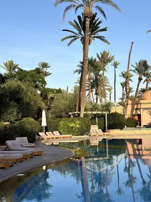 a swimming pool with chairs and a palm tree at Appartement à Marrakech in Marrakech