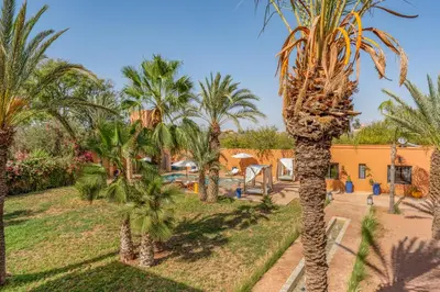 a view of a resort with palm trees at Villa Simari Palmeraie Marrakech NOUVEAU! Petit déjeuner compris-Entièrement rénovée-Superbe piscine privée chauffée-Personnel de maison inclus-Grand jardin de 2000m2-Terrain de pétanque-Ambiance typique berbère-Havre de paix in Marrakech