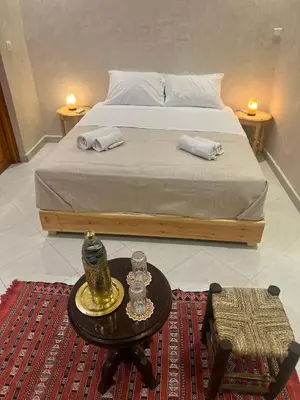 a bedroom with a bed and a table with a nightstand at Riad dar lakbira in Marrakech
