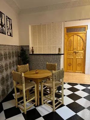 a dining room with a wooden table and chairs at Riad dar lakbira in Marrakech