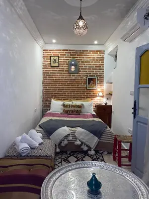 a bedroom with a bed and a brick wall at Maison Imane Marrakech in Marrakech
