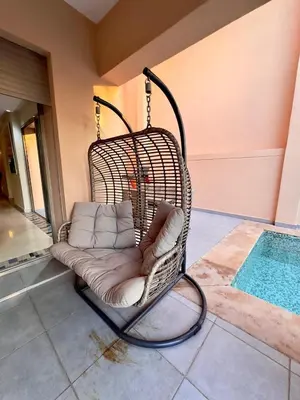 a wicker swing chair sitting next to a pool at فيلا فاخرة في مراكش مع حديقة خاصة ومسبح - تجربة استرخاء لا تُنسى in Marrakech