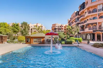 a pool with two people sitting under an umbrella at Luxury Residence with 2 Terraces Pool and Garden View Security and Self Check-in in Marrakech