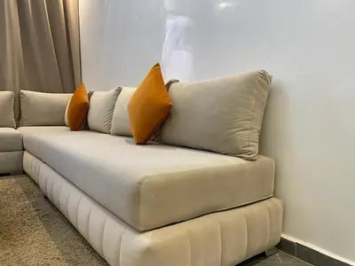 a white couch with two orange pillows on it at Location appartement a Marrakech aboib gulez in Marrakech