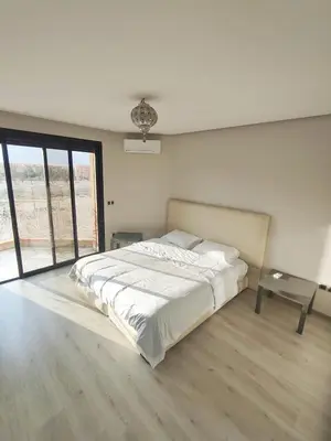 a white bedroom with a large bed and a table at Appartement calme, proche de toutes commodités in Marrakech
