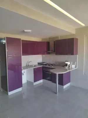 an empty kitchen with purple cabinets and a table at Appartement calme, proche de toutes commodités in Marrakech