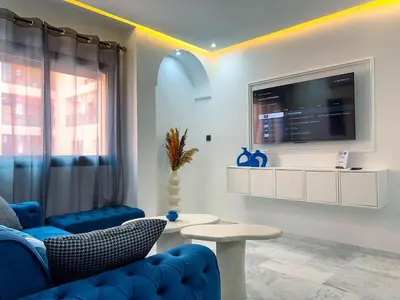 a living room with blue chairs and a tv at Royal CinemaBedroom Gueliz Center in Marrakech