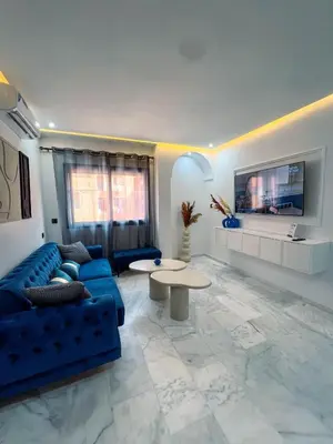 a living room with a blue couch and a table at Royal CinemaBedroom Gueliz Center in Marrakech