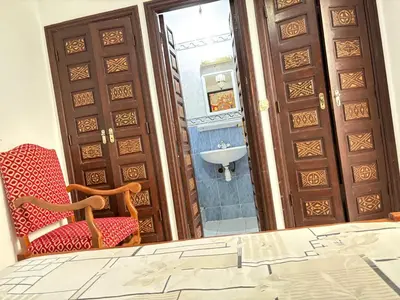 a bathroom with a mirror and a chair and a sink at LOGEMENT ENTIER MARRAKECh G26 N 35 in Marrakech