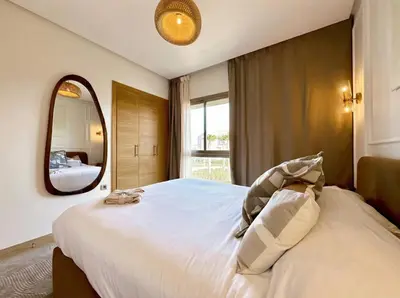 a bedroom with a large white bed with a mirror at Prestigia Saphir Luxury 3 Bedrooms, Pool & Golf View, near Airport in Marrakech