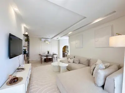 a white living room with a couch and a tv at Prestigia Saphir Luxury 3 Bedrooms, Pool & Golf View, near Airport in Marrakech