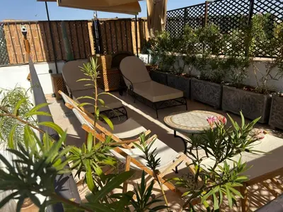 a patio with two chairs and a table and some plants at Riad Yuna in Marrakech