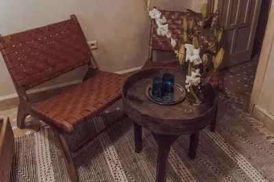 a table with a vase of flowers and two chairs at Riad Valentine in Marrakech