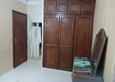 a room with a large wooden wardrobe and a chair at appartement meuble in Marrakech