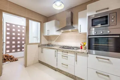 a kitchen with white cabinets and stainless steel appliances at Waterfront - Garden Level - Prestigia in Marrakech