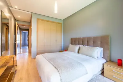 a bedroom with a large white bed and a wooden floor at Waterfront - Garden Level - Prestigia in Marrakech