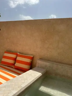 a bed with orange and white pillows next to a pool at Riad Dar Chalyia, private, 6 people, pool in Marrakech
