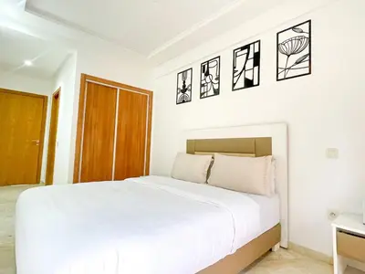 a white bedroom with a white bed and some pictures on the wall at Luxury Aprt 2 bedrooms Pool Hivernage City Centre in Marrakech