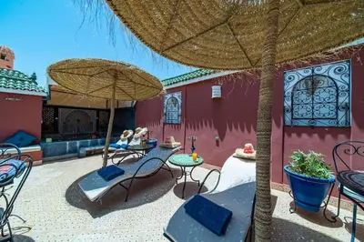 a patio with chairs and tables and an umbrella at Riad Khadoj-Marrakech-Traditional in Marrakech
