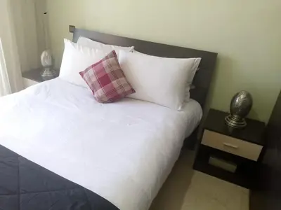 a bed with white sheets and a plaid pillow on it at Appartement au cœur de Gueliz in Marrakech