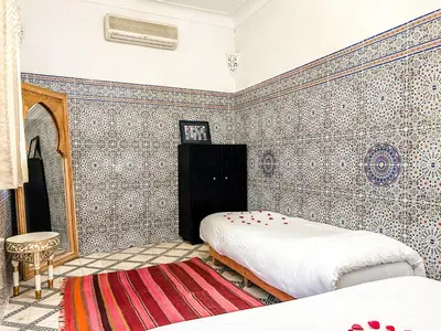 a bedroom with a bed and a tiled wall at Riad Sifaw & Spa Marrakech in Marrakech