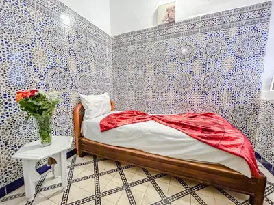 a bedroom with a bed and a vase of flowers on a table at Riad Sifaw & Spa Marrakech in Marrakech