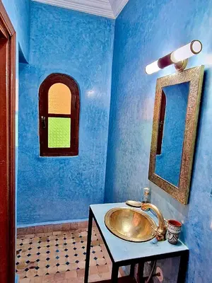 a blue bathroom with a sink and a mirror at Riad TESS in Marrakech