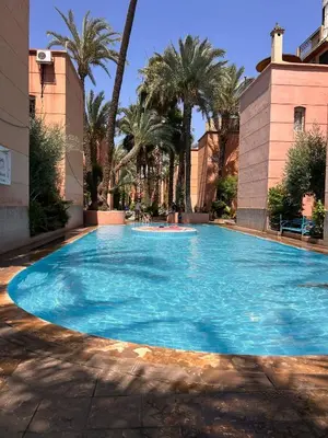 a large blue swimming pool with palm trees at Riad TESS in Marrakech