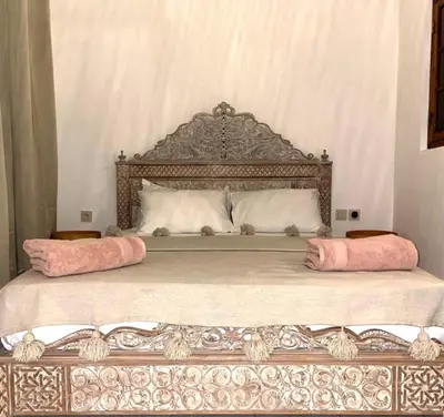 a bed with two pink pillows on top of it at Riad with 3 Swimming Pools in Marrakech