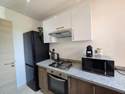 a kitchen with a microwave and a black refrigerator at Appartement Cosy - vue Piscine - Prestigia JADE in Marrakech