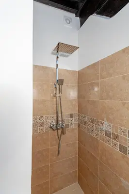 a bathroom with a shower with brown tile at Riad GUENAOUA in Marrakech