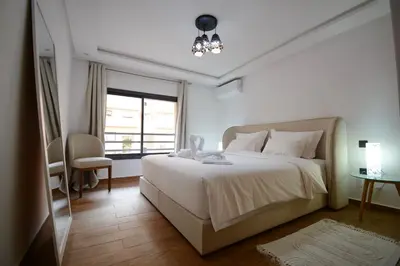a bedroom with a large white bed and a window at Duplex Safiya Suites and Services in Marrakech