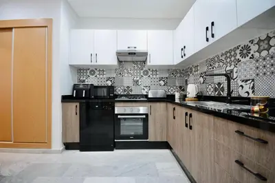 a kitchen with white cabinets and black appliances at Duplex Safiya Suites and Services in Marrakech