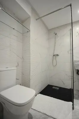 a white bathroom with a toilet and a shower at Duplex Safiya Suites and Services in Marrakech