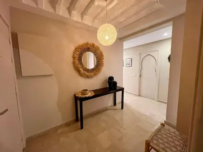 a hallway with a table and a mirror on the wall at Appartement idyllique au centre ville in Marrakech