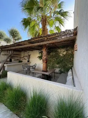 a patio with a table and chairs and a palm tree at Run Villa Marine, Elegant Private Villa in Marrakech with Heated Pool Option in Marrakech