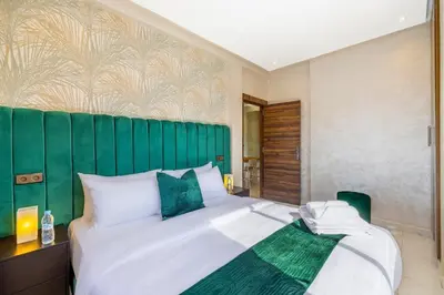 a bedroom with a large bed with a green headboard at Cocon Chaleureux au Cœur de la Ville in Marrakech