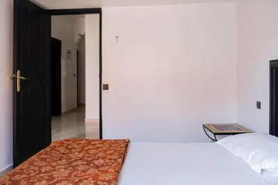 a bedroom with a white bed and a door to a hallway at Hotel Appart HB in Marrakech